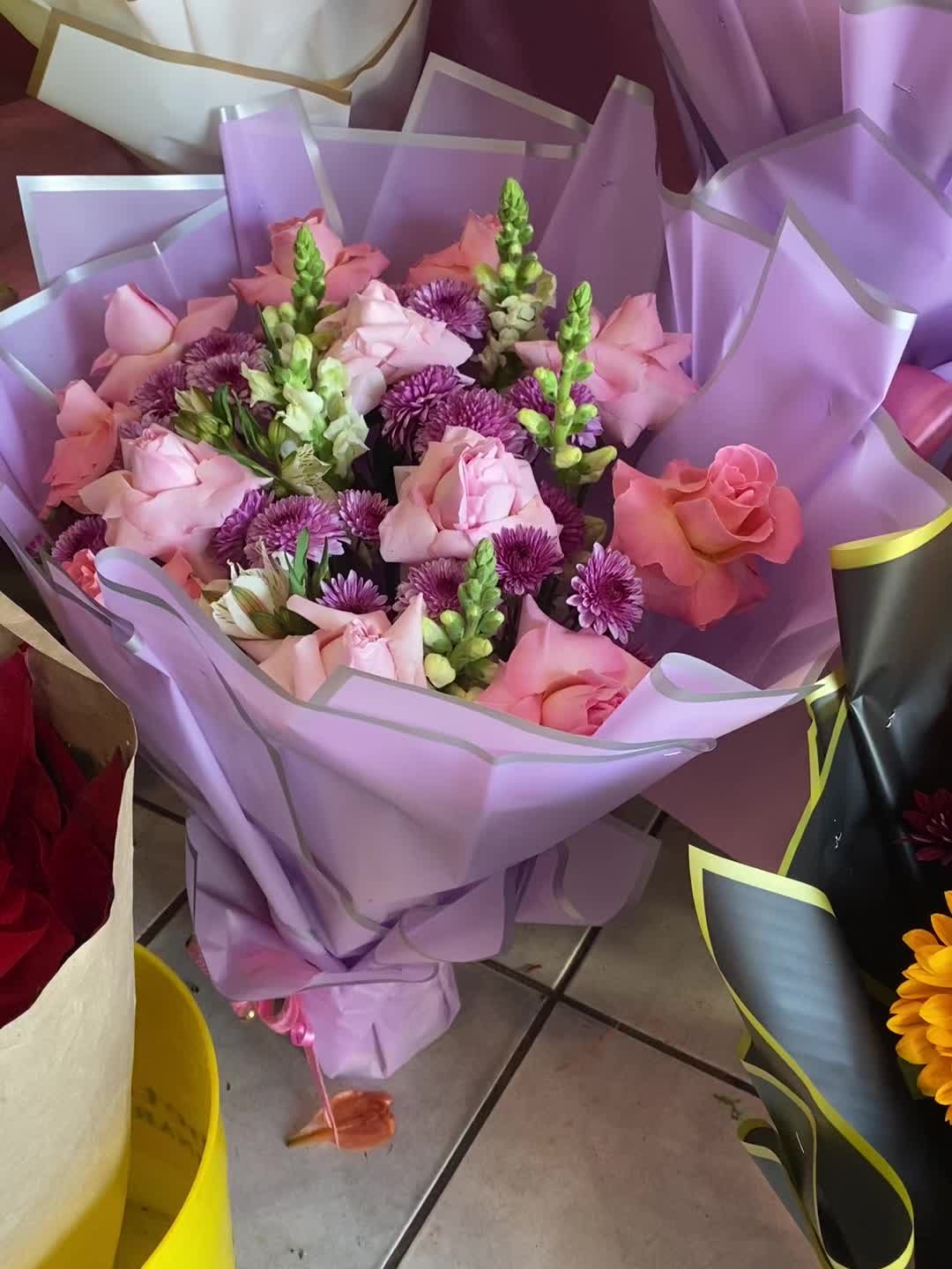 Ramo de rosas y flores lilas envuelto en papel morado