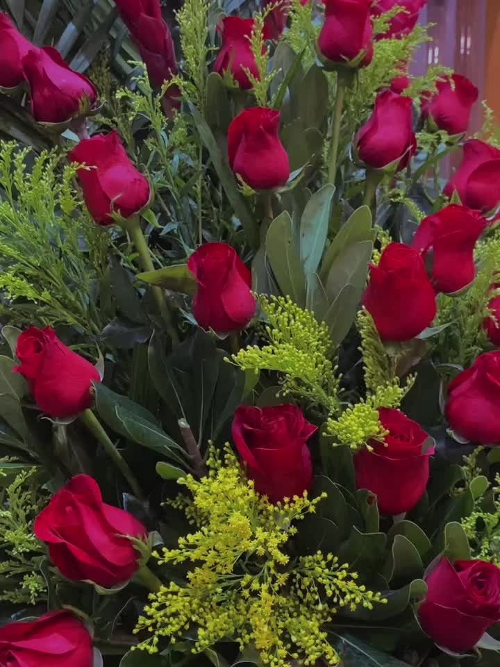 Rosas rojas con solidago en un arreglo alto